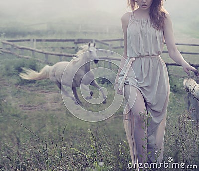 Delicate brunette posing with horse in the background Stock Photo