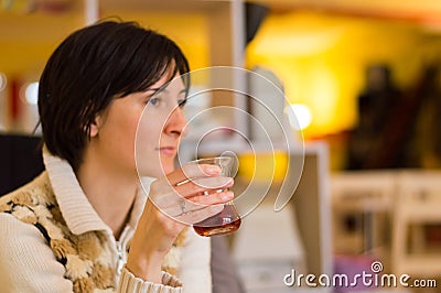 Delicate caucasian woman with short brown hair holding a glass of tea. Stock Photo