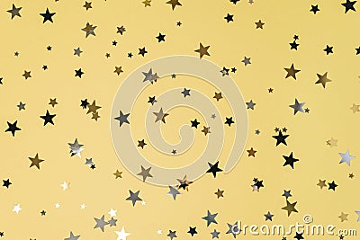 Delicate glitter star confetti on yellow background. Stock Photo