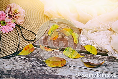 delicate scarf, hat and golden dry leaves on old wooden table outdoor in the park. Stock Photo