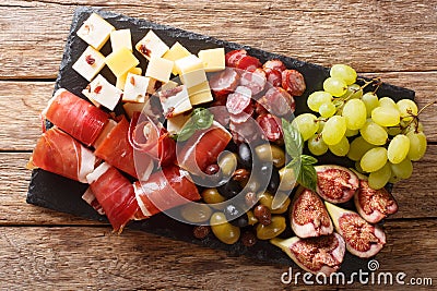 Delicious appetizer of antipasti from cheese, prosciutto ham, grapes, figs, sausages and olives close-up on a table. horizontal Stock Photo