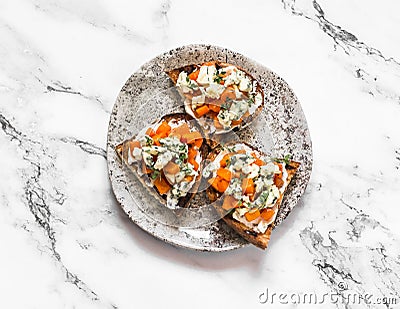 Delicious appetizer, tapas, aperitif - roasted pumpkin, gorgonzola, honey, thyme bruschetta on a light background, top view Stock Photo