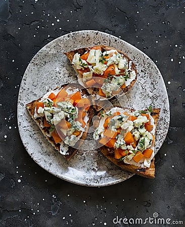 Delicious appetizer, tapas - baked pumpkin, gorgonzola, honey, thyme bruschetta on a dark background, top view Stock Photo