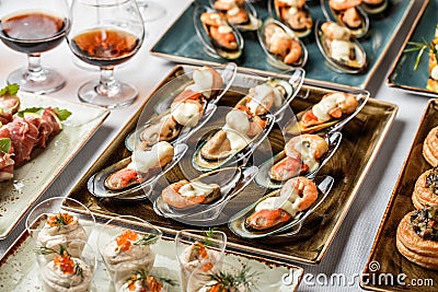 Delicious appetizers with mussels, shrimp and cheese sauce on banquet table. Gourmet food close up, snack, antipasti Stock Photo