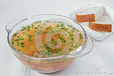 Delicious, appetizing light brown soup with herbs in a transparent plate. Bread in a white plate. Horizontal frame Stock Photo