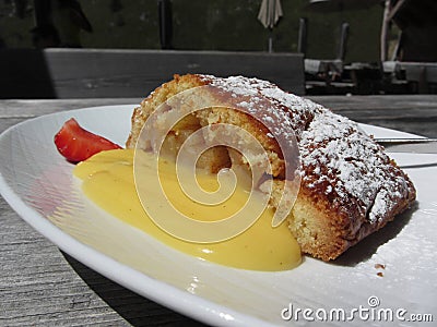 Delicious apple Strudel with vanilla cream on rustic outdoor wooden table at summer . Typical south tyrolean specialty Stock Photo