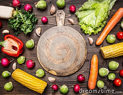Delicious assortment of farm fresh various vegetables lined frame with a chopping board in the middle on wooden rustic background Stock Photo
