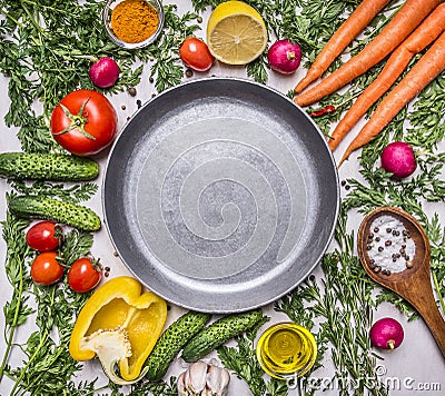 Delicious assortment of farm fresh vegetables, cucumbers, peppers, lemon, cherry tomatoes, oil, salt spoon laid around the pan Stock Photo