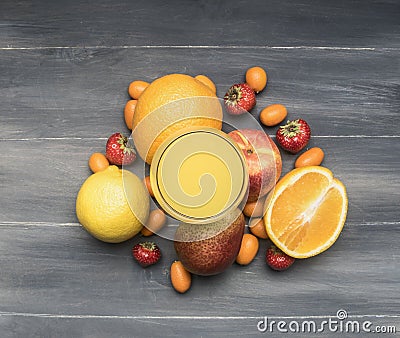 Delicious assortment of fresh variety of fruits lined around a glass with juice, kumquat, strawberry, oranges, pear, lemon, on a w Stock Photo