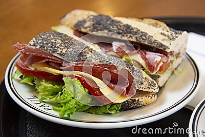 Delicious baguette sandwich with ham and salami served on a plate in a bekery shop in London. Stock Photo