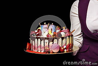 delicious beautiful multicolored cake with the number 50 is held by a girl on a dark background Stock Photo