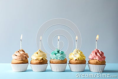 Delicious birthday cupcakes with candles on light background Stock Photo