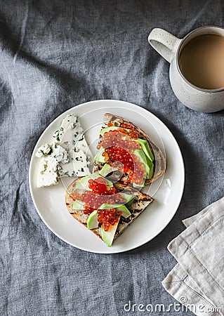 Delicious breakfast or snack - red caviar, avocado sandwiches and blue cheese on grey background Stock Photo