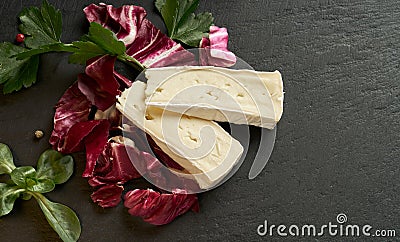 Delicious brie cheese with lavender on black background. Brie type of cheese. Camembert. Fresh Brie cheese and a slice on stone Stock Photo