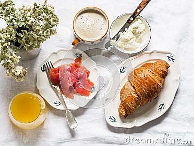 Delicious brunch, breakfast - cappuccino, croissant, cream cheese, smoked salmon, orange juice on a light background, top view Stock Photo