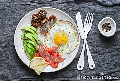 Delicious brunch - fried egg, avocado, cherry tomatoes and smoked salmon on grey background Stock Photo