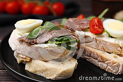 Delicious bruschettas with anchovies, cream cheese, arugula, eggs and tomatoes on table, closeup Stock Photo