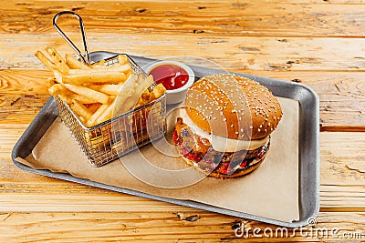 Delicious burger with sauce in a tray with a basket of french fries and ketchup on it Stock Photo