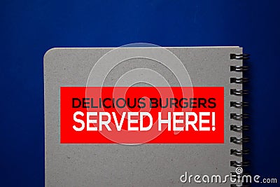 Delicious Burgers Served Here! write on a book isolated on blue background Stock Photo