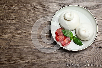 Delicious burrata cheese with basil and cut tomato on wooden table, top view. Space for text Stock Photo