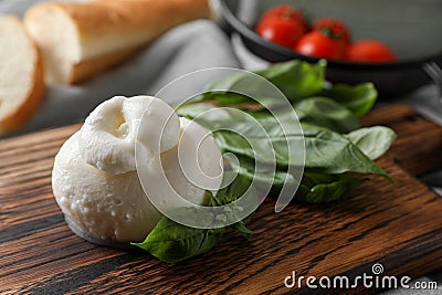 Delicious burrata cheese with basil on wooden board, closeup. Space for text Stock Photo