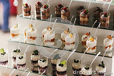 Delicious candy bar at wedding reception. White and chocolate desserts with fruits and cream, cupcakes on stand, modern sweet Stock Photo