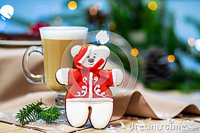 Delicious cappucino glass cup with christmas teddy bear gingerbread cookie. fireflies and spruce branches background Stock Photo
