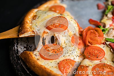 Cheese stringy slice lifted of full supreme vegan pizza baked fresh out of the oven next to ingredients Stock Photo