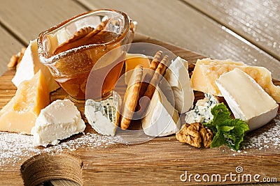 Tasting cheese dish on a wooden plate. Food for wine and romantic, cheese delicatessen on a wooden rustic table. Top Stock Photo
