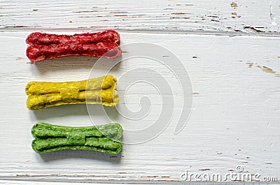 Delicious chewing colored bones for dogs with different tastes on white wooden background Stock Photo