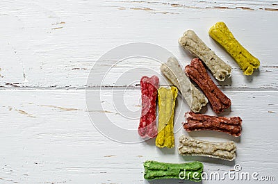 Delicious chewing colored bones for dogs with different tastes on white wooden background Stock Photo