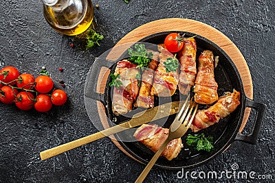 Delicious chicken rolls wrapped in strips of bacon on a cast-iron frying pan. Concept healthy and balanced eating. place for text Stock Photo