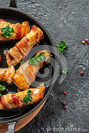 Delicious chicken rolls wrapped in strips of bacon on a cast-iron frying pan. Concept healthy and balanced eating. place for text Stock Photo