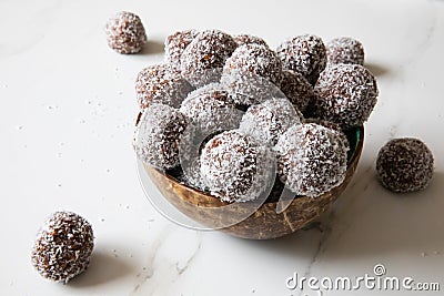 Delicious Coconut-Chocolate balls covered with grated coconut served in a coconut plate against white background Stock Photo