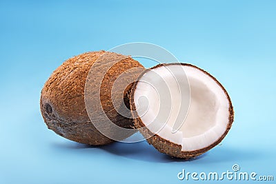 Delicious coconuts on a saturated blue background. Tropical coconut cut in pieces. Nutritious organic ingredients. Stock Photo
