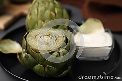 Delicious cooked artichokes with tasty sauce on plate, closeup Stock Photo