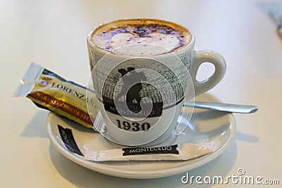 A delicious cup of chocolate sprinkled cappuccino coffee with a biscuit is served in a small restaurant in Playa Las Americas in T Editorial Stock Photo