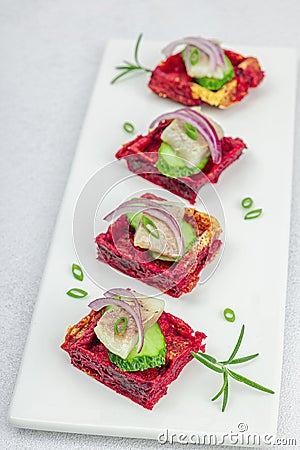 A delicious festive appetizer with herring on pieces of beet waffles with spices and sauce Stock Photo