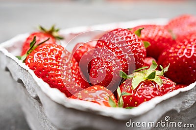 Delicious fragrant strawberries in a paper container, on the table. Red ripe berry is ready to eat. Stock Photo