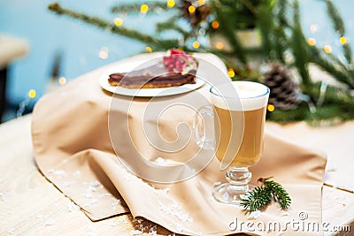 Delicious fresh festive morning cappuccino coffee in a glass cup and cupcake dessert on the wooden table, fireflies and spruce Stock Photo