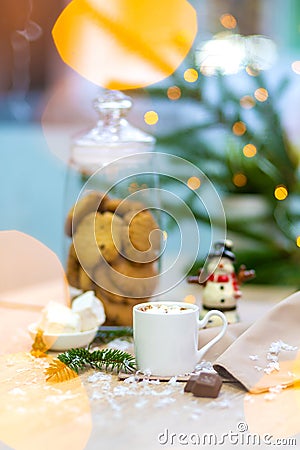 Delicious fresh festive morning cappuccino coffee in a white cup with marshmallow.Glass bottle with cookies. fireflies and spruce Stock Photo