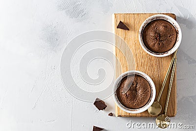 Delicious fresh fondant with hot chocolate centre in ceramic molds on wooden board on white background. Lava cake recipe, menu. Stock Photo
