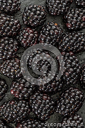Delicious fresh and ripe blackberries and reddish garnet. With drops of water. On textured background in black color.With yellow l Stock Photo