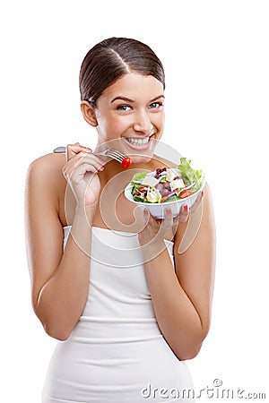 Delicious freshness. Portrait of a beautiful young woman standing with a bowl of salad against a white background. Stock Photo