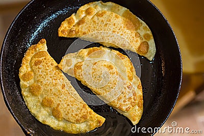 Delicious fried pies with meat and greens cheburek in a pan with oil Stock Photo