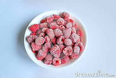 Delicious frozen raspberries in a white bowl. Stock Photo