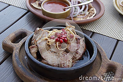 Delicious Georgian cuisine. fried meat in a clay pan, served with onions and pomegranate seeds Stock Photo