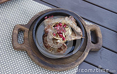 Delicious Georgian cuisine. fried meat in a clay pan, served with onions and pomegranate seeds Stock Photo