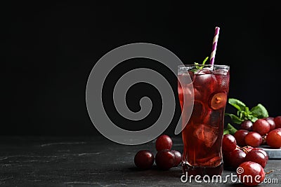 Delicious grape soda water on black table, space for text. Refreshing drink Stock Photo