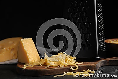 Delicious grated cheese on wooden board against background Stock Photo